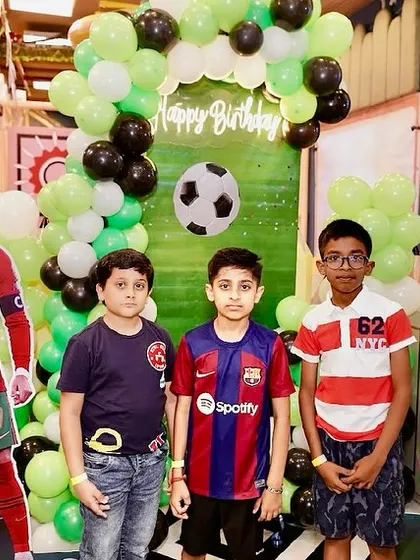 Young football fans posing in front of the themed backdrop at a birthday party.