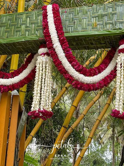 A close-up of the intricate floral garlands on the coconut leaf arch.