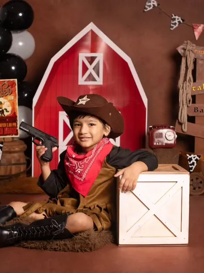 This four-year-old is all smiles, posing with his toy gun in our fun cowboy and barnyard themed shoot.