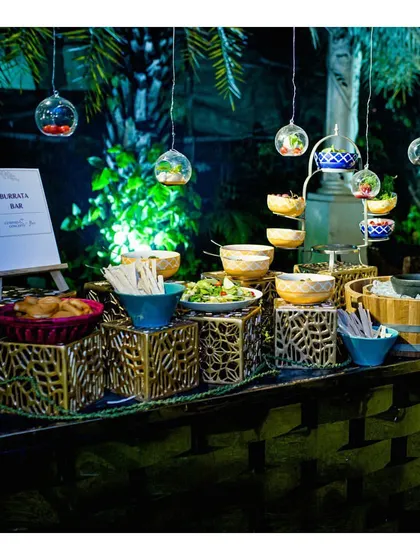 A wider view of the Burrata Bar, showcasing the unique presentation with hanging glass orbs and an array of fresh accompaniments.