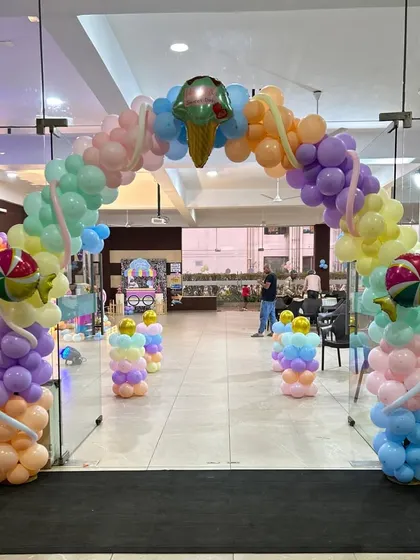 A grand entrance for a Candyland party, with a pastel balloon arch decorated with ice cream and candy foil balloons.