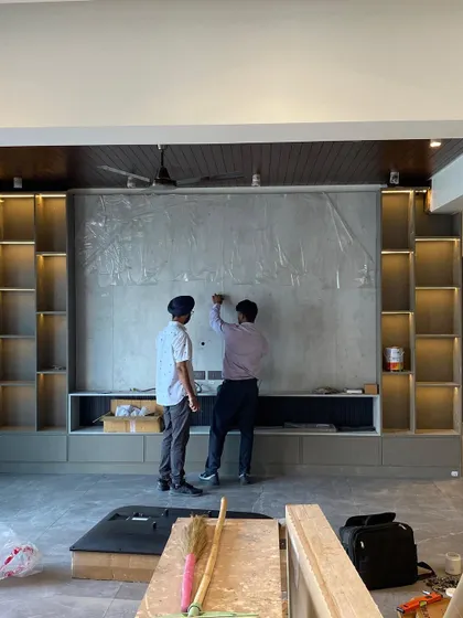 A mid-process shot of our team meticulously planning the layout on a micro-concrete accent wall. This behind-the-scenes view shows the precision and hands-on approach we take to execute complex design elements.