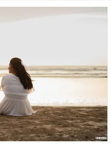 A serene pre-wedding portrait of the bride-to-be sitting on the beach, gazing at the tranquil sea.