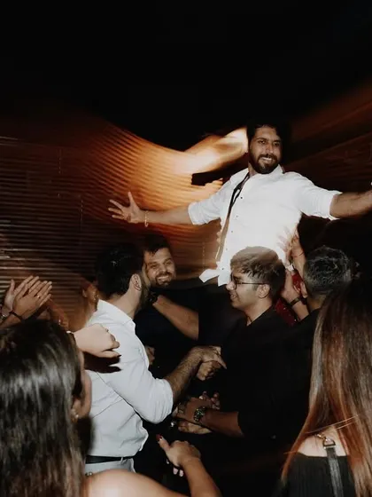 The groom is the life of the party, lifted onto the shoulders of his friends on the dance floor.
