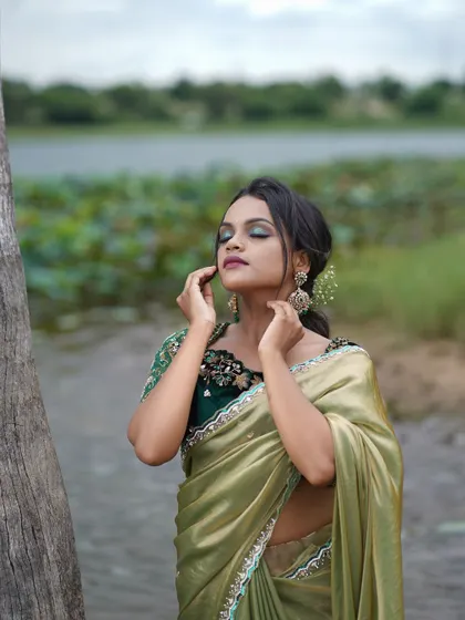 An elegant olive green satin saree, perfect for an outdoor photoshoot or a sophisticated evening event.