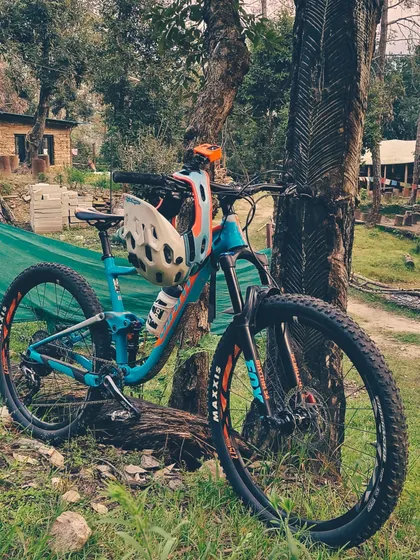 A full-suspension Giant mountain bike taking a rest against a tree. We believe in using quality gear that can handle the tough Himalayan trails.
