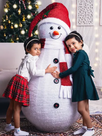Twin girls give our friendly studio snowman a big hug, their matching outfits adding to the cuteness.