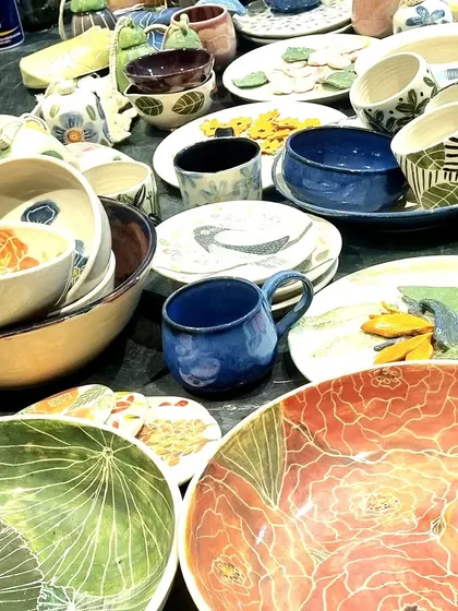 A glimpse of my stall at a pop up, filled with a variety of my handmade ceramics. You can see large floral platters, hand-painted mugs with geometric patterns, and an assortment of bowls, each with its own distinct character and glaze.