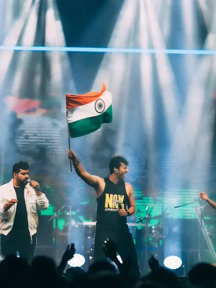 The band celebrating on stage with the Indian flag at the conclusion of their performance at ISB.