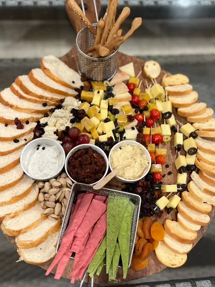 This is our artfully arranged cheese and charcuterie board, a feast for the eyes and the palate. It’s generously packed with artisanal cheeses, crackers, breads, nuts, fresh fruits, and savory dips, perfect for social gatherings.