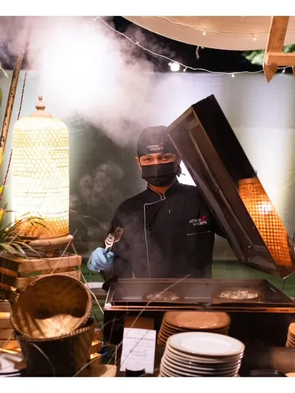 A dramatic shot of a chef at a live station, with steam billowing around them, creating a theatrical culinary moment.