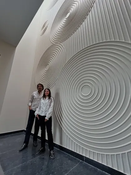 Posing in front of the dramatic, double-height wall with a concentric circle design at the 'House of Passages'. This feature turns a simple corridor into a work of art.