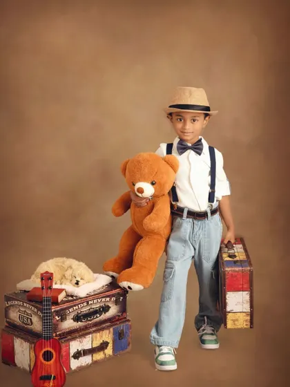 Ready to go with his teddy bear companion and suitcase in hand. This shot captures the excitement and wonder of childhood adventures.