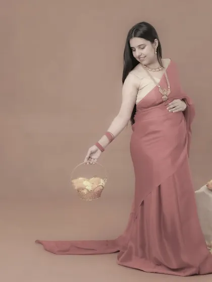 A simple and elegant portrait of a mom-to-be in a pink saree, holding a basket of flowers. The soft, monochromatic edit gives this traditional photo a timeless and artistic feel.