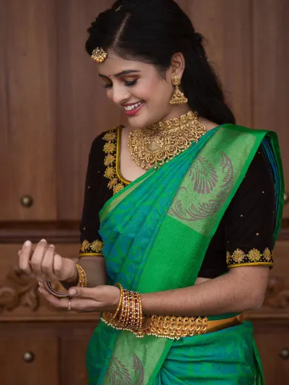 A candid moment showing the full effect of the traditional look. The green silk saree, gold jewellery, and glowing makeup come together for a timeless and elegant style.