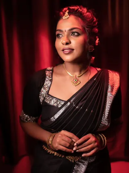 A model posing in a black saree, with a confident and bold expression.