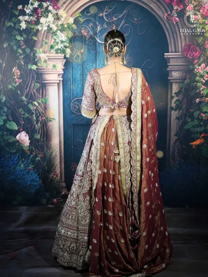 The back view of this bridal ensemble showcases an elegant hair bun and the beautiful draping of the dupatta. Every detail, from the hairstyle to the outfit, is carefully curated for a complete look.