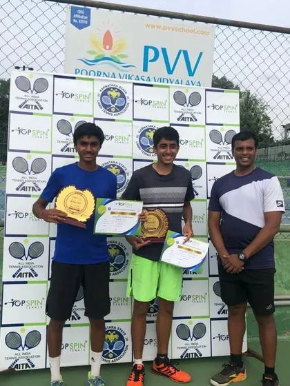 The U-18 doubles champions posing with their certificates and trophies, a proud moment for the players and their coach.