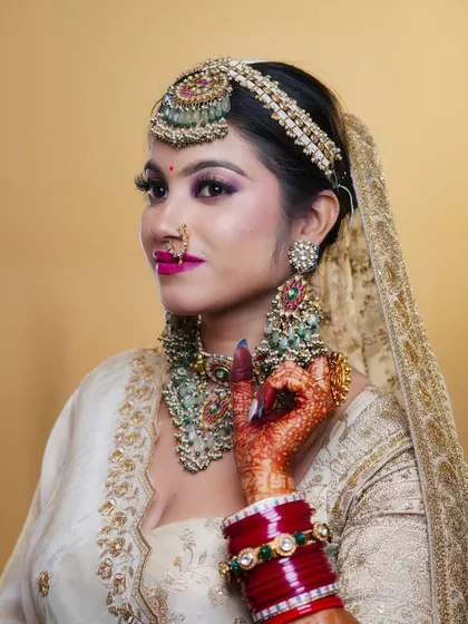 This student's bridal creation features a stunning combination of an off-white lehenga with bold, colorful jewelry, showcasing their understanding of contrast and balance.