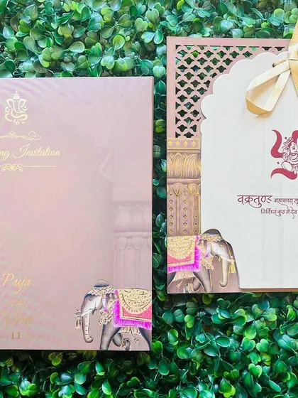 This pastel pink invitation features a laser-cut sleeve with an arch design and elephant motifs. The insert includes Sanskrit shlokas for a truly traditional touch.