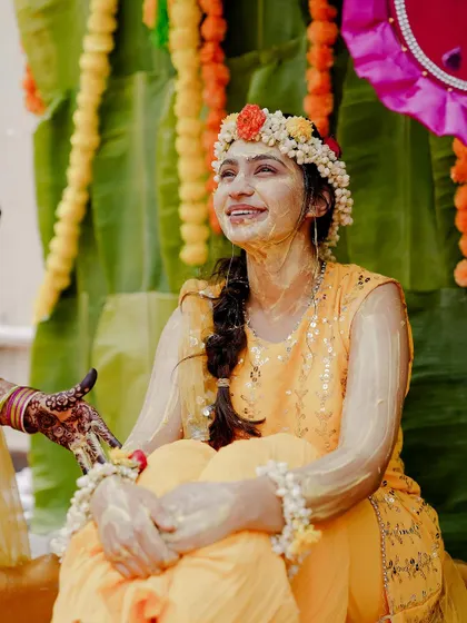 A beautiful candid of the bride, smiling as she sits amidst the Haldi decor, ready for the ceremony to begin.