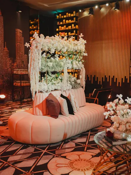 A chic lounge sofa set against a backdrop of a city skyline and a wall of flowers, providing a stylish and comfortable spot for guests to relax.