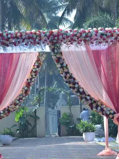 An entrance arch for a resort wedding, using peach and pink drapes with floral arrangements that blend beautifully with the outdoor setting.