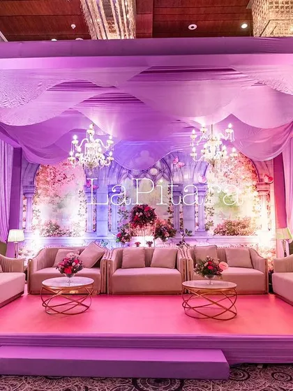 An elegant lounge seating area for adults at the enchanted garden party, with plush sofas and beautiful purple drapery.