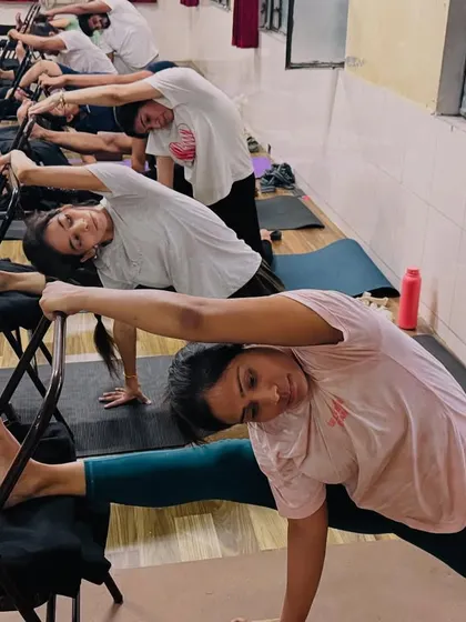 Our students use chairs for support in a deep side stretch. This modification allows them to focus on lengthening the side body without worrying about balance.