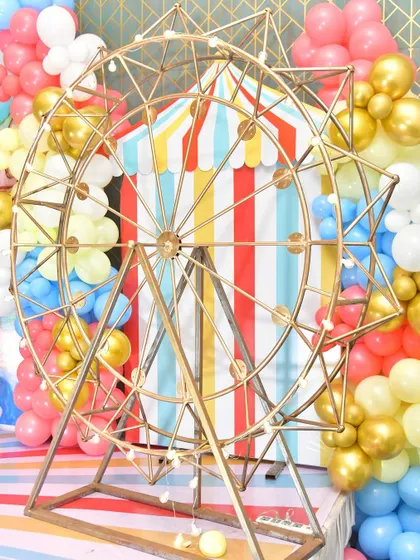 A large golden ferris wheel prop that adds a touch of magic to this carnival-themed party.