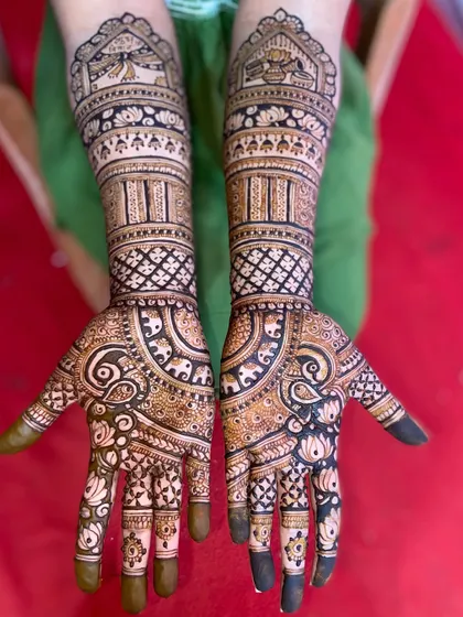 This design is filled with auspicious symbols, including elephants, paisleys, and lotus flowers, creating a dense and traditional bridal look.