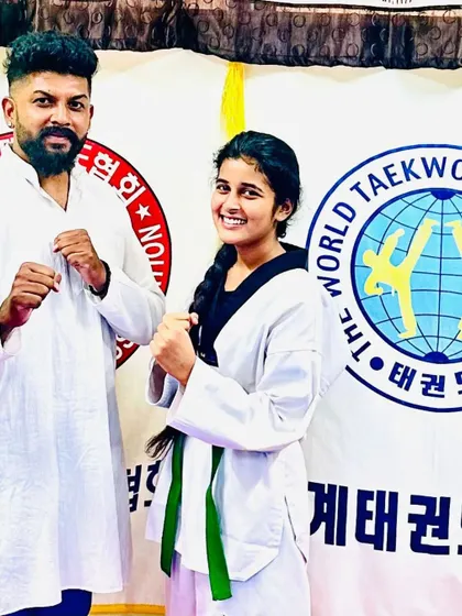 A student and coach pose after a successful belt promotion.