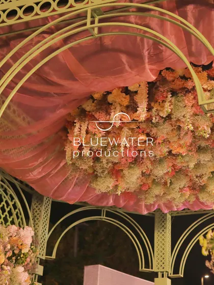 A view looking up into the ceiling of the French garden mandap, showing the layers of pink fabric and hanging florals.
