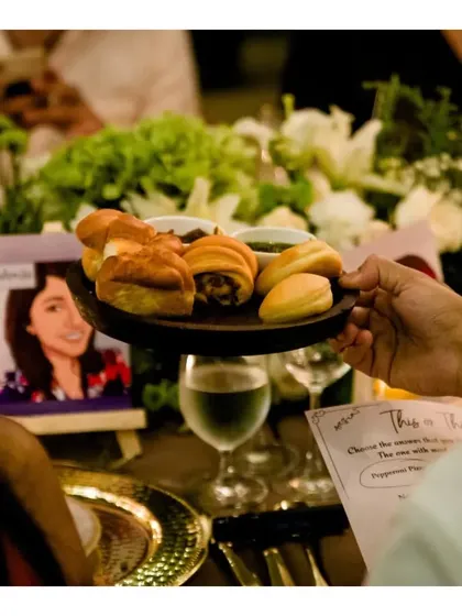 A server presenting a platter of freshly baked assorted breads to guests at a sit-down dinner, a small detail that enhances the overall dining experience.