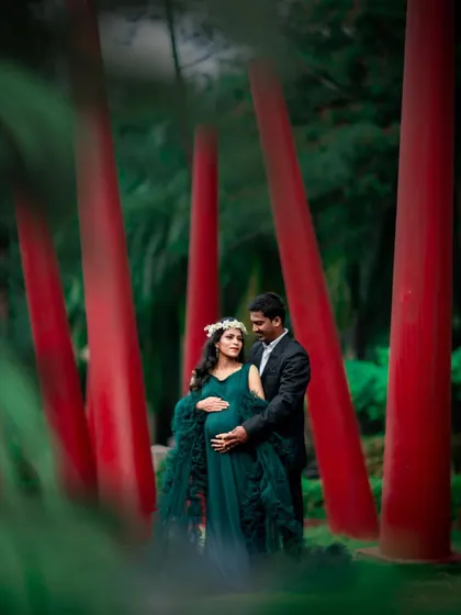 A striking couple's portrait set against a modern art installation. The contrast of the red pillars and green foliage makes this photo pop.