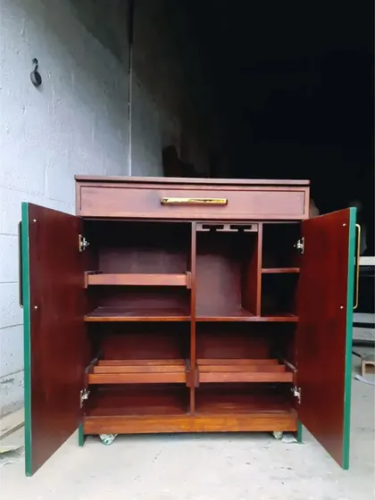 The interior of the green bar cabinet, revealing well-organized storage with shelves, a wine rack, and glass holders.