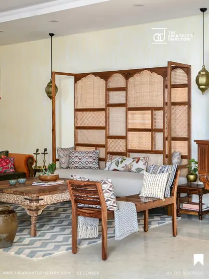 A wider view of the living area, showcasing the large cane-backed sofa and a mix of antique and modern furniture.