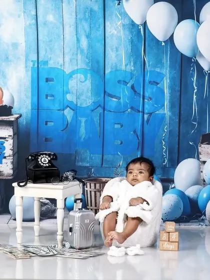 A newborn version of the Boss Baby theme, with the baby wrapped in a white robe in a tiny armchair.
