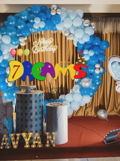 A simple yet charming animal-themed decoration. This setup uses a full circle balloon arch in blue and silver with large elephant and lion cutouts, perfect for a first birthday party.