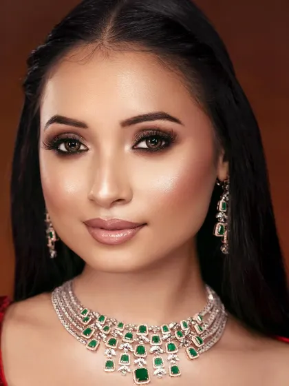 A perfect beauty close-up showcasing a soft smokey eye and radiant skin, complemented by a stunning emerald and diamond necklace.