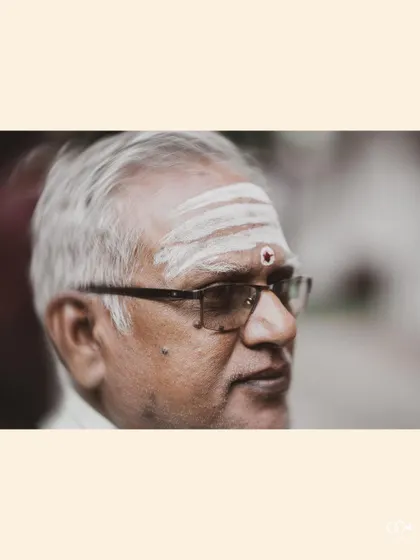 A powerful close-up portrait of an elderly family member with traditional markings, watching the ceremony.
