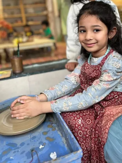A young girl smiles proudly at her work on the pottery wheel. Her confidence and happiness are what my center is all about.