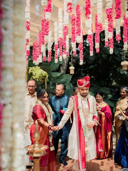 A couple walks hand-in-hand to their mandap, ready to begin their life together.