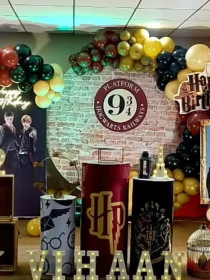 Welcome to Hogwarts! This detailed Harry Potter themed birthday party features the iconic Platform 9 3/4 brick backdrop, house color balloon garlands, and themed props like Hedwig, the sorting hat, and character standees.