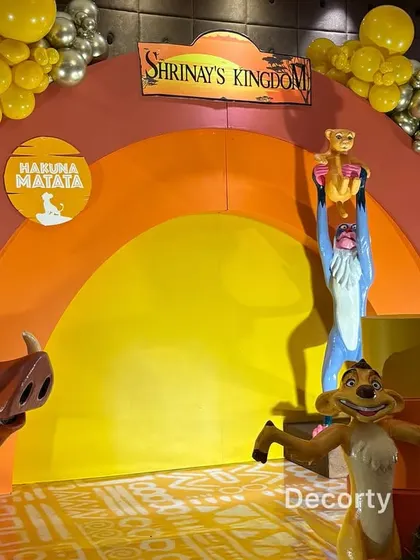 A close-up of the main stage, showing the 'Shrinay's Kingdom' sign and characters like Pumbaa and Rafiki holding up Simba.