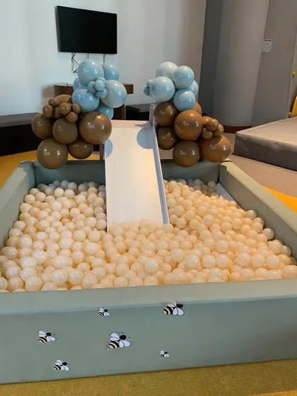 A custom ball pit for the Winnie the Pooh party, decorated with buzzing bees and balloon clusters in brown and blue.