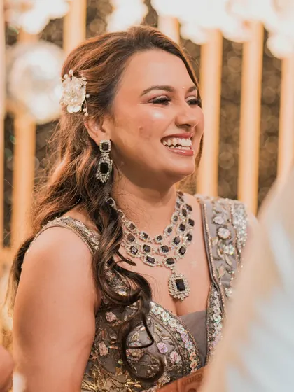 A close-up of the bride's happy face during the reception. The soft side-swept hair with a floral accessory adds a touch of romance to her glamorous look.