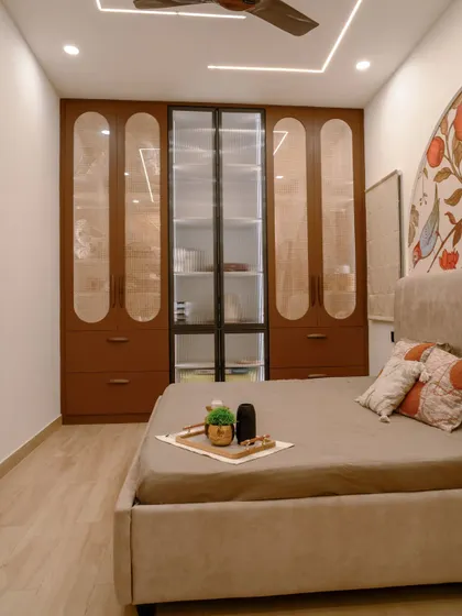 This bedroom features a custom wardrobe with glass and wood-finish doors, combining display and concealed storage.