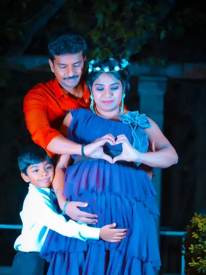 A heartwarming family maternity photo taken at night. The family makes a heart shape over the baby bump, creating a magical and intimate portrait.