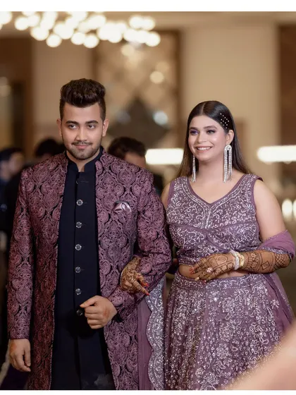 The couple makes their entrance at the engagement party, walking arm-in-arm and smiling, looking happy and in love.